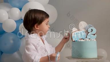 两岁的男孩带着一辆车吃一个喜庆的蓝色蛋糕